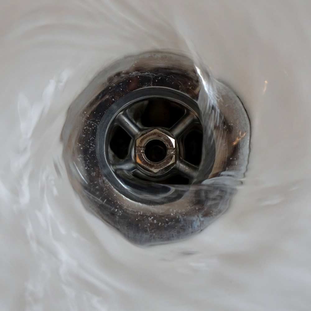 Arco plumbers in Romford. Photo of water swirling down a plug hole