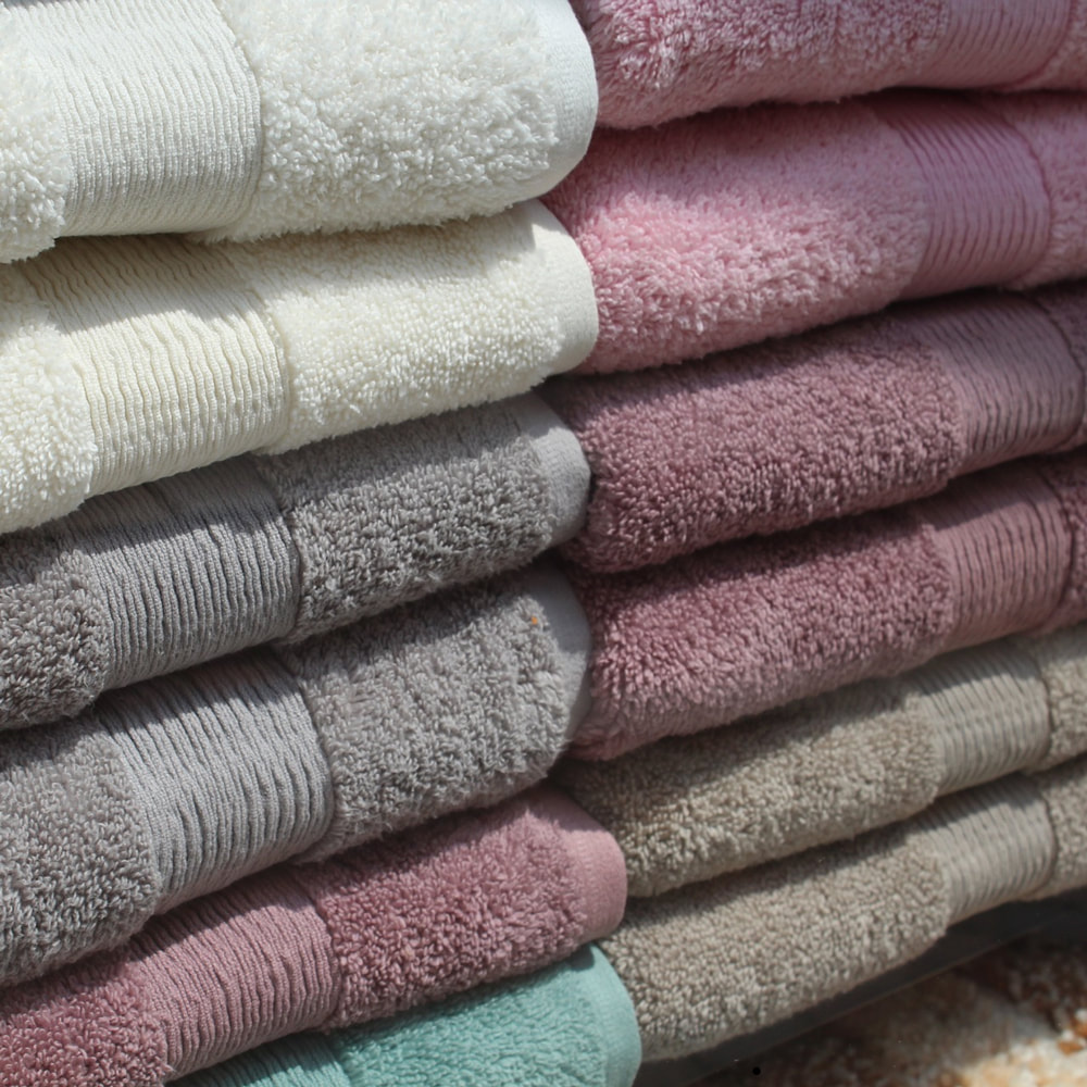 Arco fit bathrooms in Romford. Close up of a series of different coloured towels stacked in a tower.
